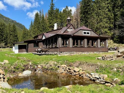 a large house with a pond in front of it at Horská Bouda v Obřím Dole in Pec pod Snezkou