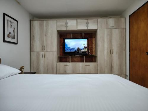 une chambre avec un lit blanc et une télévision dans l'établissement Casa Hévenie, Amplia, familiar, cómoda y bien ubicada, à El Poblado