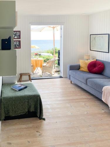 a living room with a blue couch and a view of the ocean at Beachfront House At Hølken Beach in Odder
