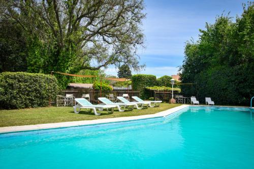 ラ・クンブレにあるHostería La Viñaの白いラウンジチェア付きのスイミングプールを利用できます。