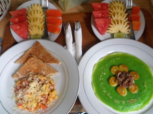 three plates of food on a table with green soup at Putu's Paradise Guesthouse in Ubud