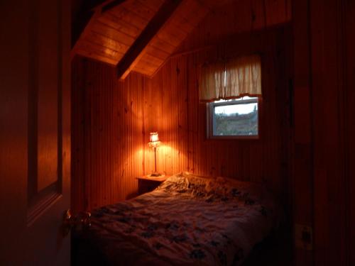 1 dormitorio con 1 cama en una habitación con ventana en Les Chalets Brise-de-Mer, en Sainte-Thérèse-de-Gaspé