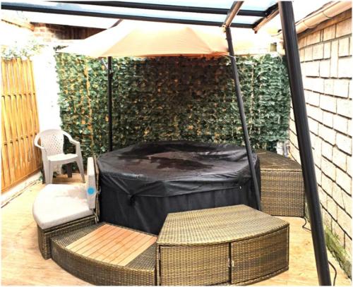 a patio with an umbrella and a chair and a table at SPACIEUX Appart Jacuzzi Terrasse Parking 10min port d'Honfleur Plage in Honfleur