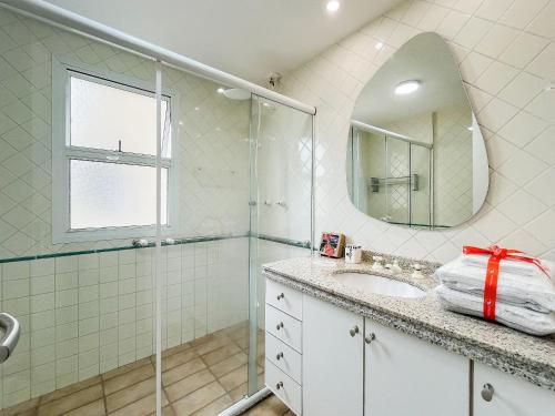 a bathroom with a shower and a sink and a mirror at Riviera | Aconchegante e Charmoso - Enxoval Compl in Riviera de São Lourenço