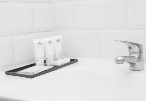 a bathroom sink with three rolls of toilet paper on a shelf at The Diplomat Studio by Cape Living in Cape Town