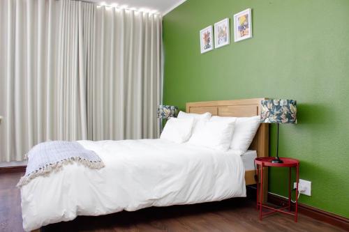 a bedroom with green walls and a bed with white pillows at The Diplomat Studio by Cape Living in Cape Town