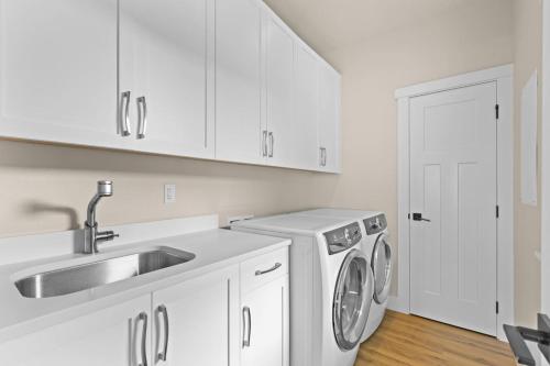 Una cocina blanca con fregadero y lavadora. en Ainamalu, en Waikoloa