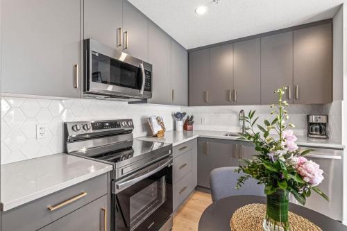 a kitchen with stainless steel appliances and a table with a vase of flowers at Chick and Cozy Haven near Banff with Hot tub and Pool in Canmore