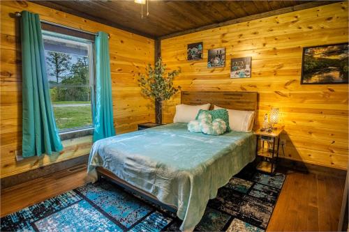 ein Schlafzimmer mit einem Bett in einer Blockhütte in der Unterkunft Forest Gap - Pizza oven, hot tub, EV charger in Hico