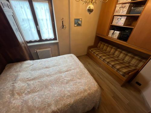 a bedroom with a bed and a bench in front of a window at Holiday PratoNevoso - Sci ai piedi in Prato Nevoso