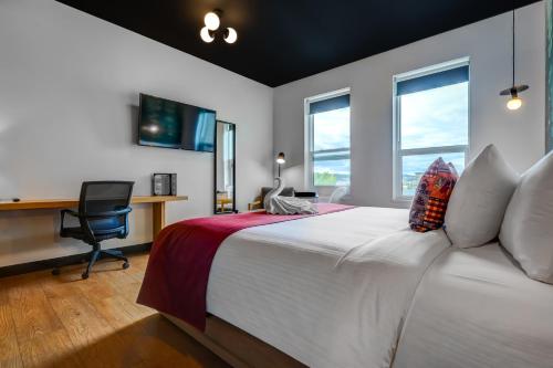 a bedroom with a bed with a desk and windows at Raven Inn Whitehorse in Whitehorse
