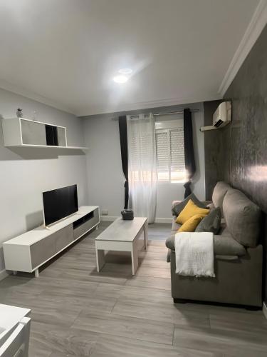 a living room with a couch and a tv at Grey House in Huelva