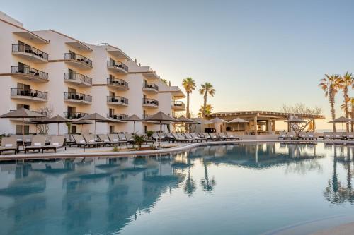 a hotel with a pool and chairs and palm trees at Villa del Palmar Beach Resort & Spa in Cabo San Lucas