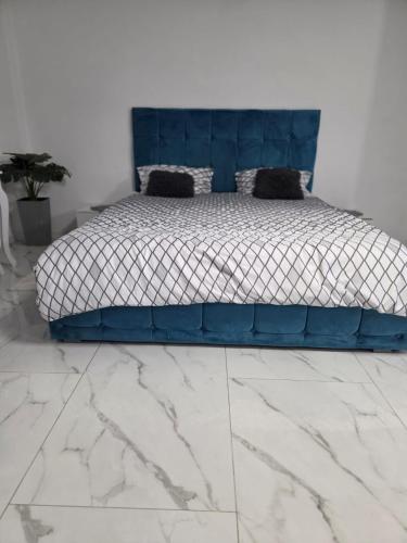 a bed with a blue headboard in a bedroom at Mary Magnolia in Craiova