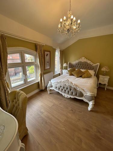 a bedroom with a white bed and a chandelier at Peacock Cottage Eaton Road in Hough Green