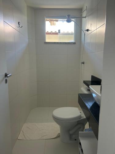 a white bathroom with a toilet and a sink at Condomínio Villa das Águas Litoral Sul de Sergipe in Estância