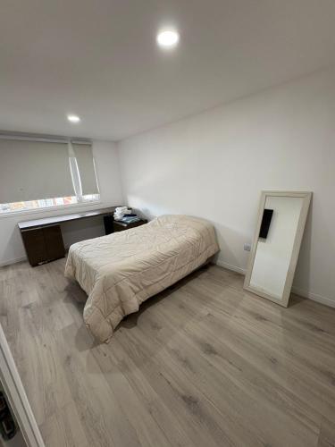 ein weißes Schlafzimmer mit einem Bett und Holzboden in der Unterkunft Dúplex barrio Aeropuerto in Río Grande