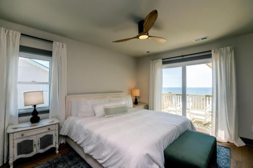 a bedroom with a bed with a ceiling fan and windows at Sulla Sabbia in Edisto Island