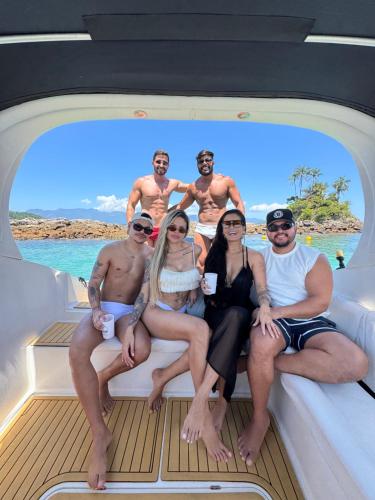 eine Gruppe von Menschen, die auf dem Heck eines Bootes sitzen in der Unterkunft Aluguel de Lancha em Angra in Angra dos Reis