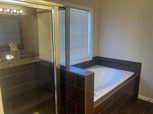 un bagno con vasca e doccia in vetro di Crestwicke Casa 75 a Jonesboro