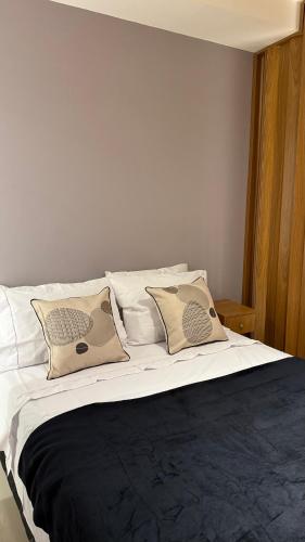 Una cama con sábanas blancas y almohadas. en Cobertura Linear no Recreio - Varanda Grande, Vista Montanhas, Próx Praia, Garagem, Acomoda até 4 pessoas, en Río de Janeiro