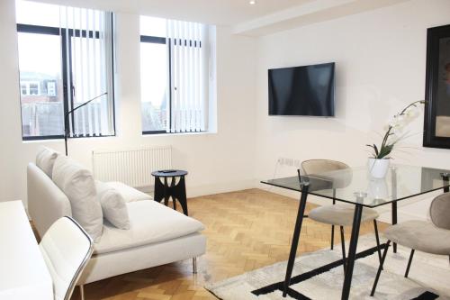 a living room with a white couch and a glass table at Chelmsford Town Centre, Modern 1 Bed Apartment in Chelmsford