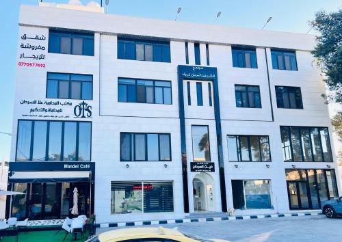 a white building with windows on a street at Zurich Furnished Apartments in Al Mafraq