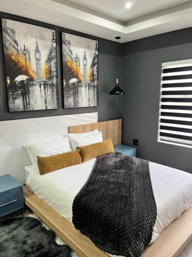 a bedroom with a bed with three pictures on the wall at 98 Inn Guesthouse Two Bedroom Apartment in Jacksonʼs Drift