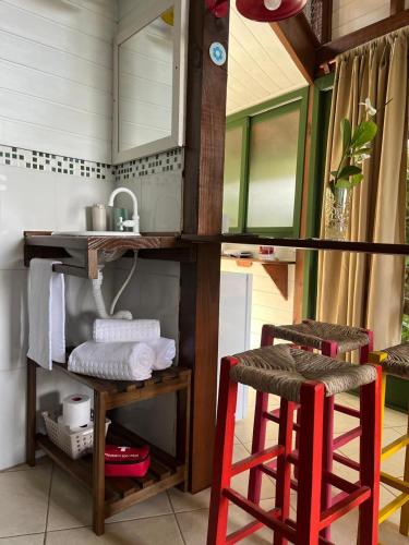 a bathroom with a sink and two red stools at Bangalô Bambu in Imbituba
