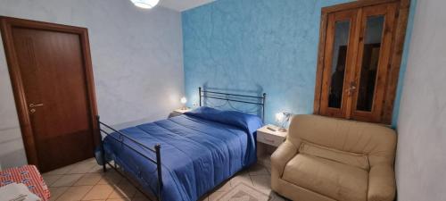 a bedroom with a blue bed and a chair at Agriturismo Conca del Re in Castrovillari