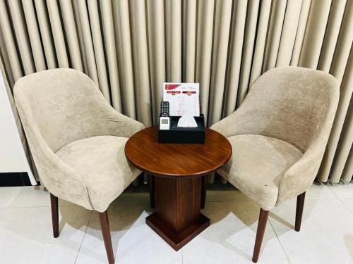 two chairs and a table with a phone on it at رغدان فيو للشقق المخدومة in Al Baha