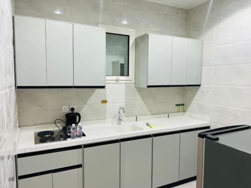 a kitchen with white cabinets and a sink at رغدان فيو للشقق المخدومة in Al Baha