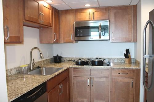 a kitchen with wooden cabinets and a sink and a microwave at Oasis Downtown Fort Myers, Pool, Parking ,Pet Friendly in Fort Myers