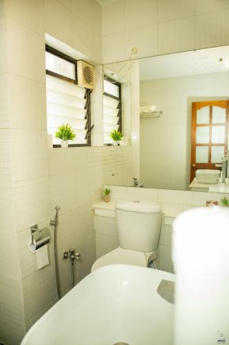 a white bathroom with a toilet and a sink at Tropical 1BHK Pool View Near Beach - Sia Stays in Candolim