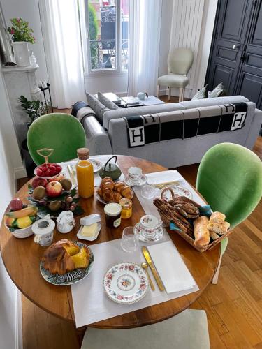 einen Tisch mit Frühstückszutaten darauf im Wohnzimmer in der Unterkunft Le Lierre et La Rose in LʼAigle