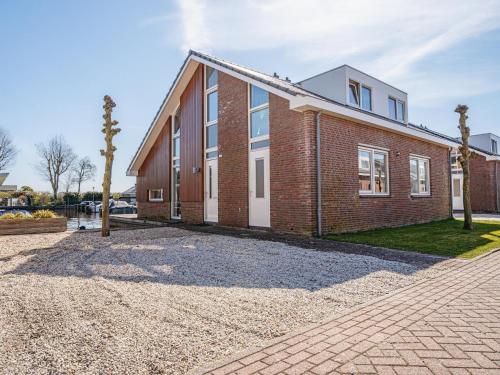 a brick house on a gravel driveway at Houseboat in Waterpark with Private Dock in Uitgeest