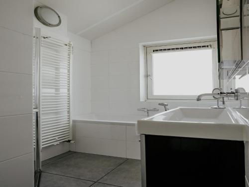 a white bathroom with a sink and a window at Houseboat in Waterpark with Private Dock in Uitgeest