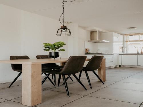 a dining room table with chairs and a potted plant at Houseboat in Waterpark with Private Dock in Uitgeest