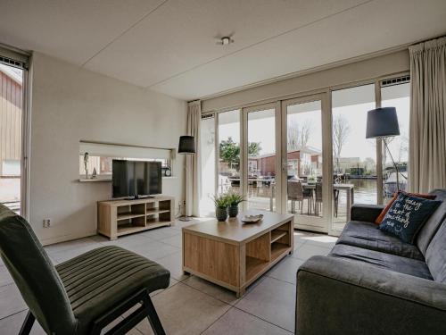 a living room with a couch and a tv at Houseboat in Waterpark with Private Dock in Uitgeest