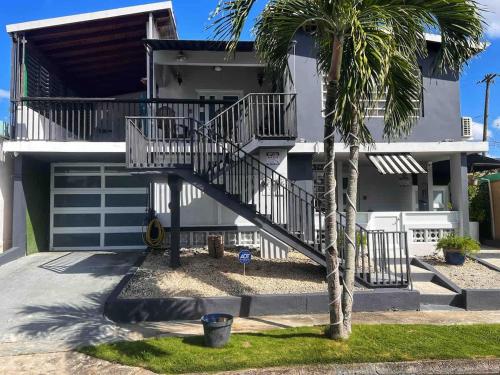 a house with a staircase in front of it with a palm tree at XELOR | Cozy Home | Generator/Cistern | Bayamón in Bayamón