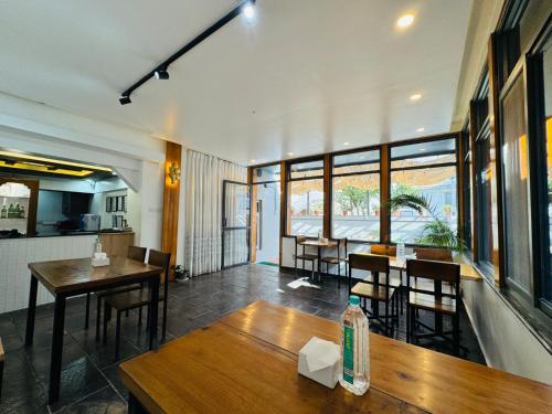 パタンにあるNavaya Residenceの木製のテーブルと椅子と窓のあるレストラン