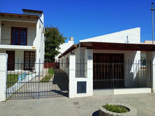 a white house with a gate in front of it at Complejo Antilhue in Las Grutas