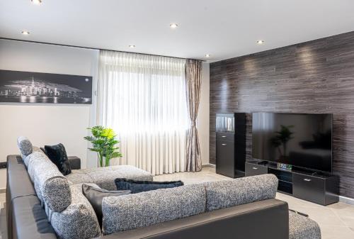 a living room with a couch and a flat screen tv at Luxury Apartment Schwabach 2 in Schwabach