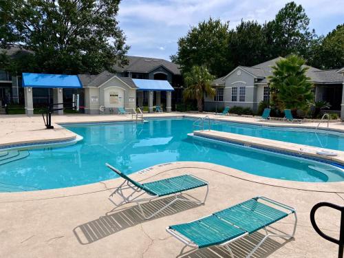a large swimming pool with two chairs in a resort at Nomad Hub,Fast Wi-Fi, King Comfort & Pool Vibes in Gainesville