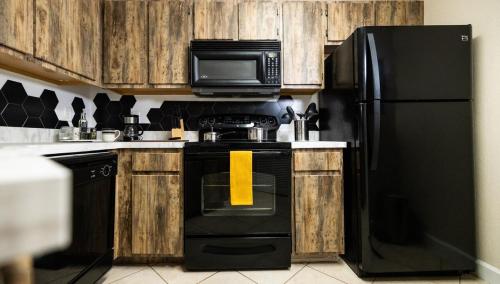 a kitchen with black appliances and wooden cabinets at Nomad Hub,Fast Wi-Fi, King Comfort & Pool Vibes in Gainesville