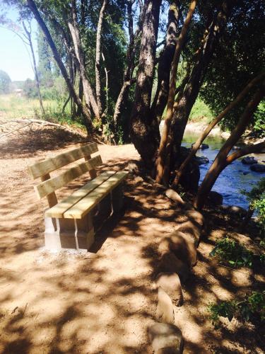 a wooden bench sitting on a dirt path next to a river at Cabañas Rahue in Vilches