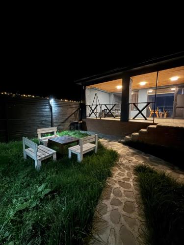 two benches and a table outside of a house at night at Shahdag Berghoff House in Qusar