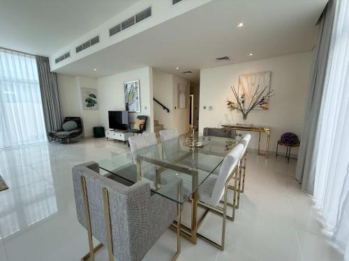 a dining room with a glass table and white chairs at Spacious Fully Furnished 6BR Villa in Damac Hill2 in ‘Ūd al Bayḑāʼ