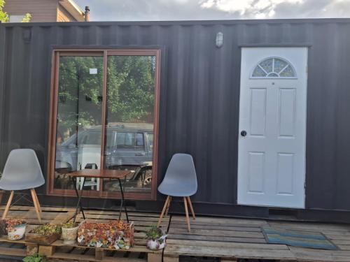 a blue shipping container with two chairs and a door at Hostal Boutique "Maryluz" in Coihaique