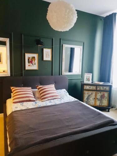 a bedroom with a large bed with green walls at Petite Charlotte in Tarnów
